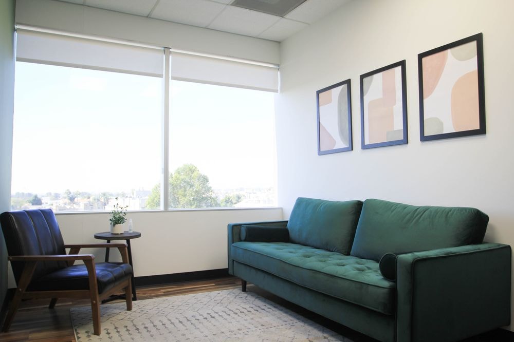 A bright therapy office lounge with a teal sofa